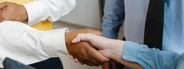 Dos personas se dan la mano tras firmar un préstamo con codeudor, que comparte la deuda con el titular principal