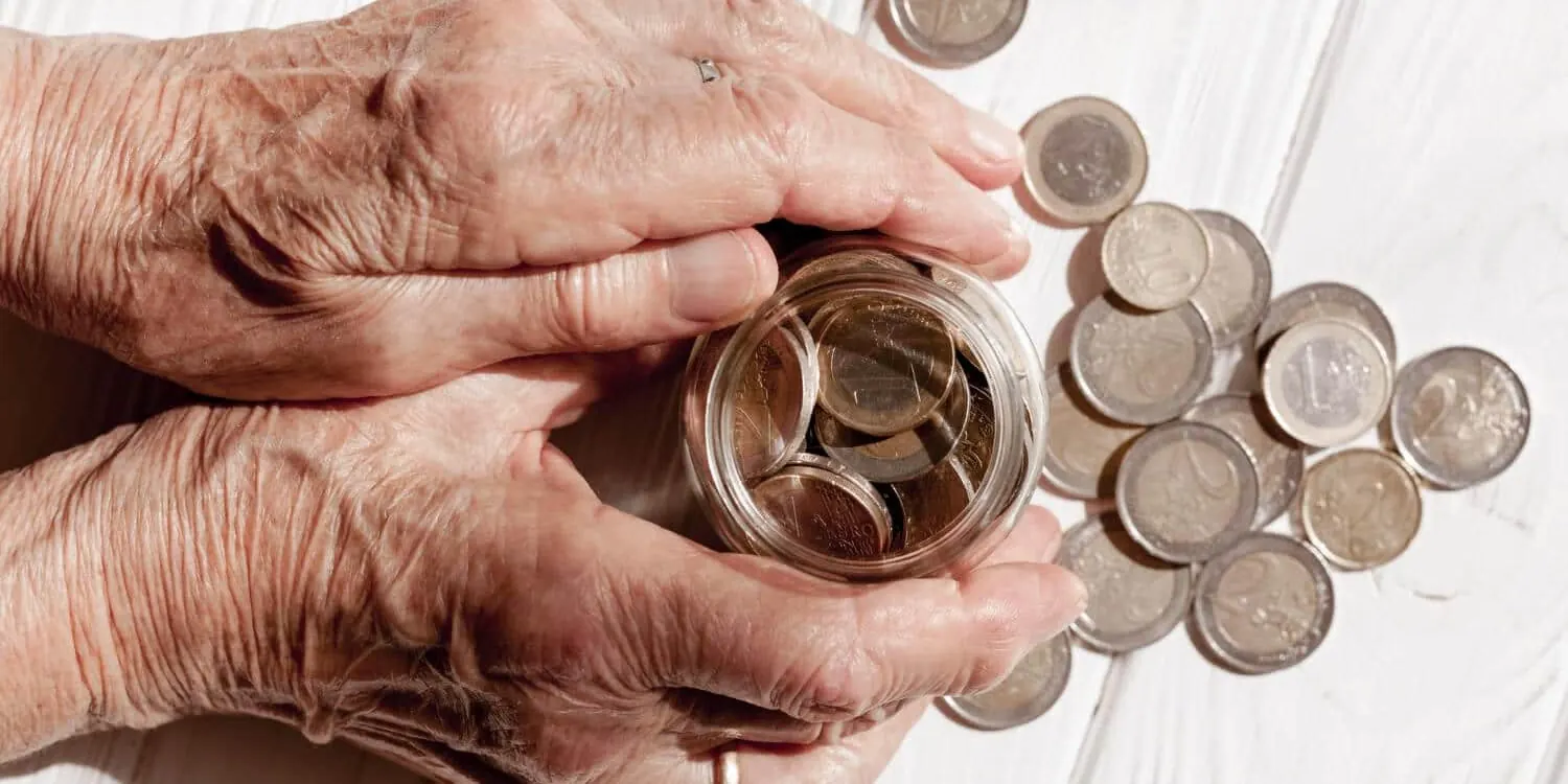 Manos de una persona mayor contando monedas: la pensión es el ingreso que decide la cuota de un préstamo personal